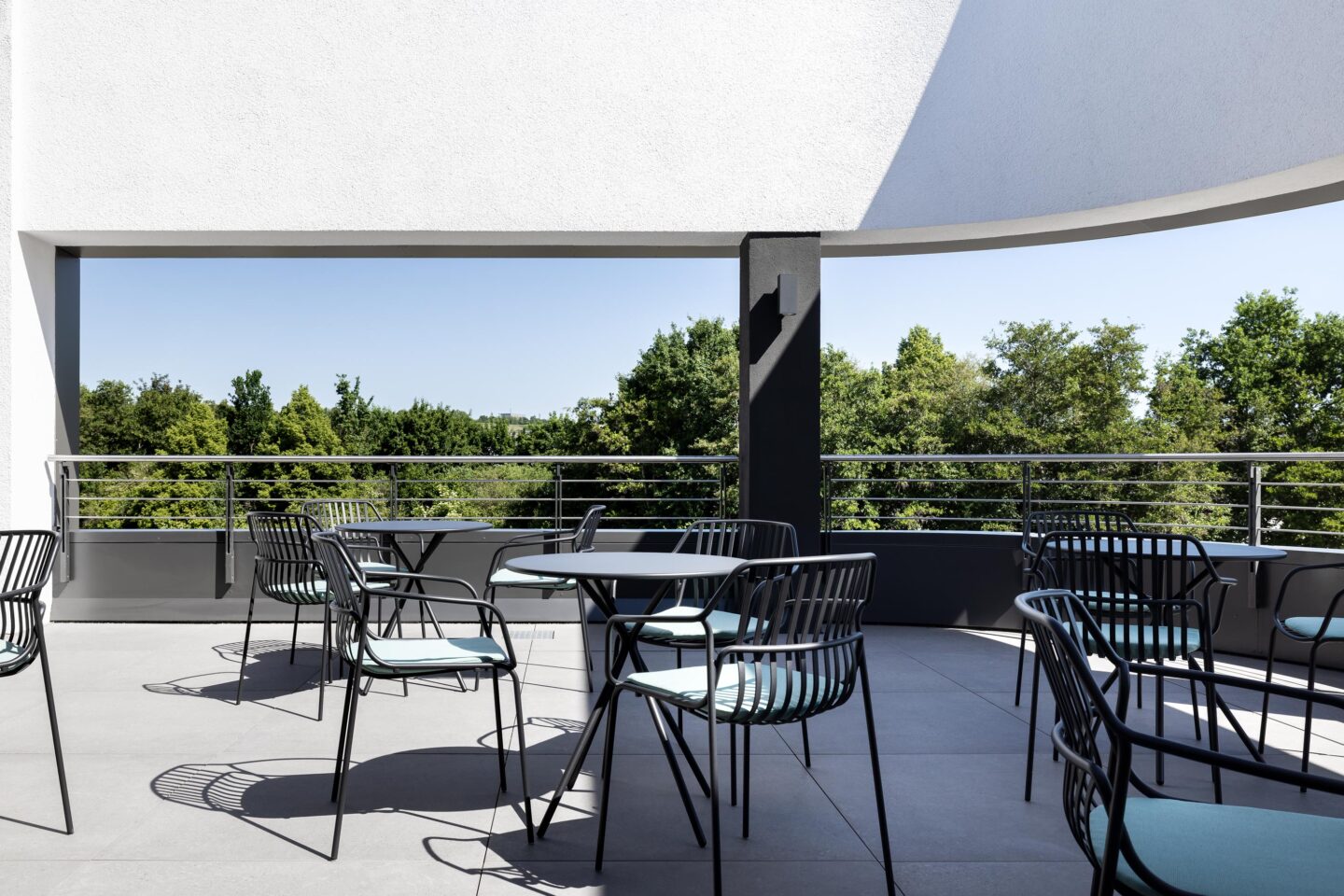 Sonnige Mitarbeiter-Dachterrasse mit modernen, grauen Outdoor-Stühlen von Brunner.