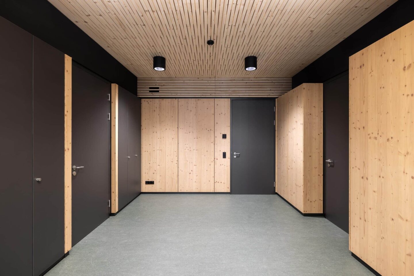 School corridor with flush-integrated feco cabinet walls in wood look and dark gray elements.