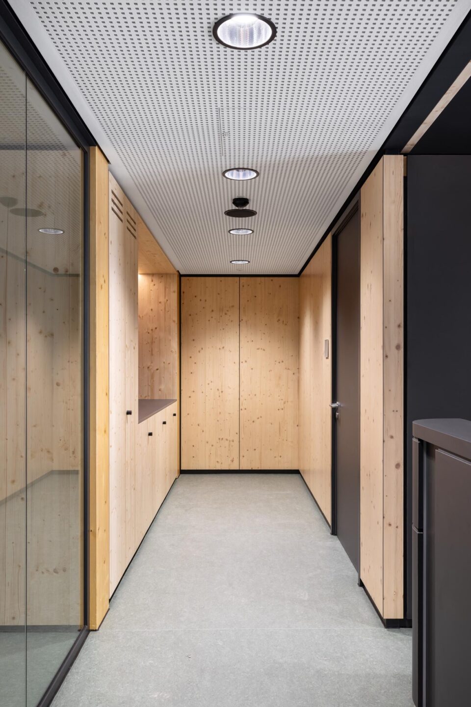 Corridor area in the new school building with wooden fixtures, acoustic ceiling, and feco wooden wall as access to the classroom cluster.