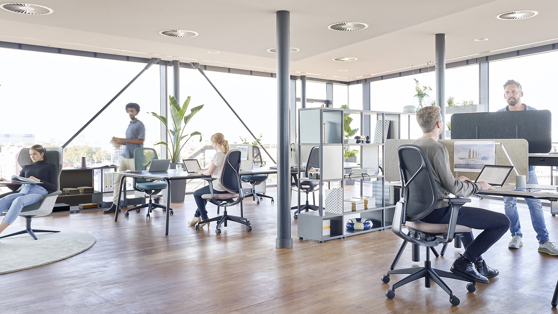 Moderne Bürolandschaft mit Mitarbeitenden an Stehtischen, Sitzplätzen und in der Lounge-Zone